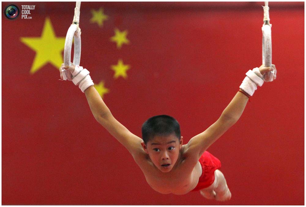 Мальчик на кольцах во время тренировки группы от 7 до 10 лет в спортивной школе Шичахай в Пекине, 18 августа 2010 года. (REUTERS/David Gray)