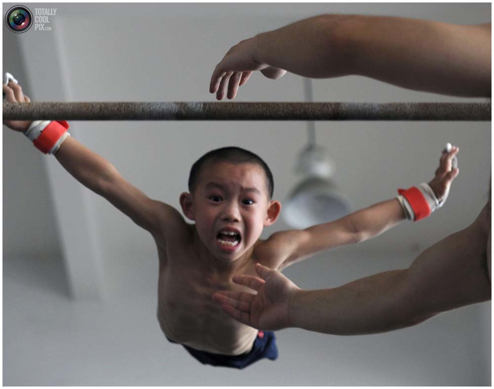 Мальчик спрыгивает с перекладины на тренировке группы 4-7 лет в гимнастическом зале в городе Цзясин, провинция Чжэцзян, 10 августа 2010 года. (REUTERS/Stringer)